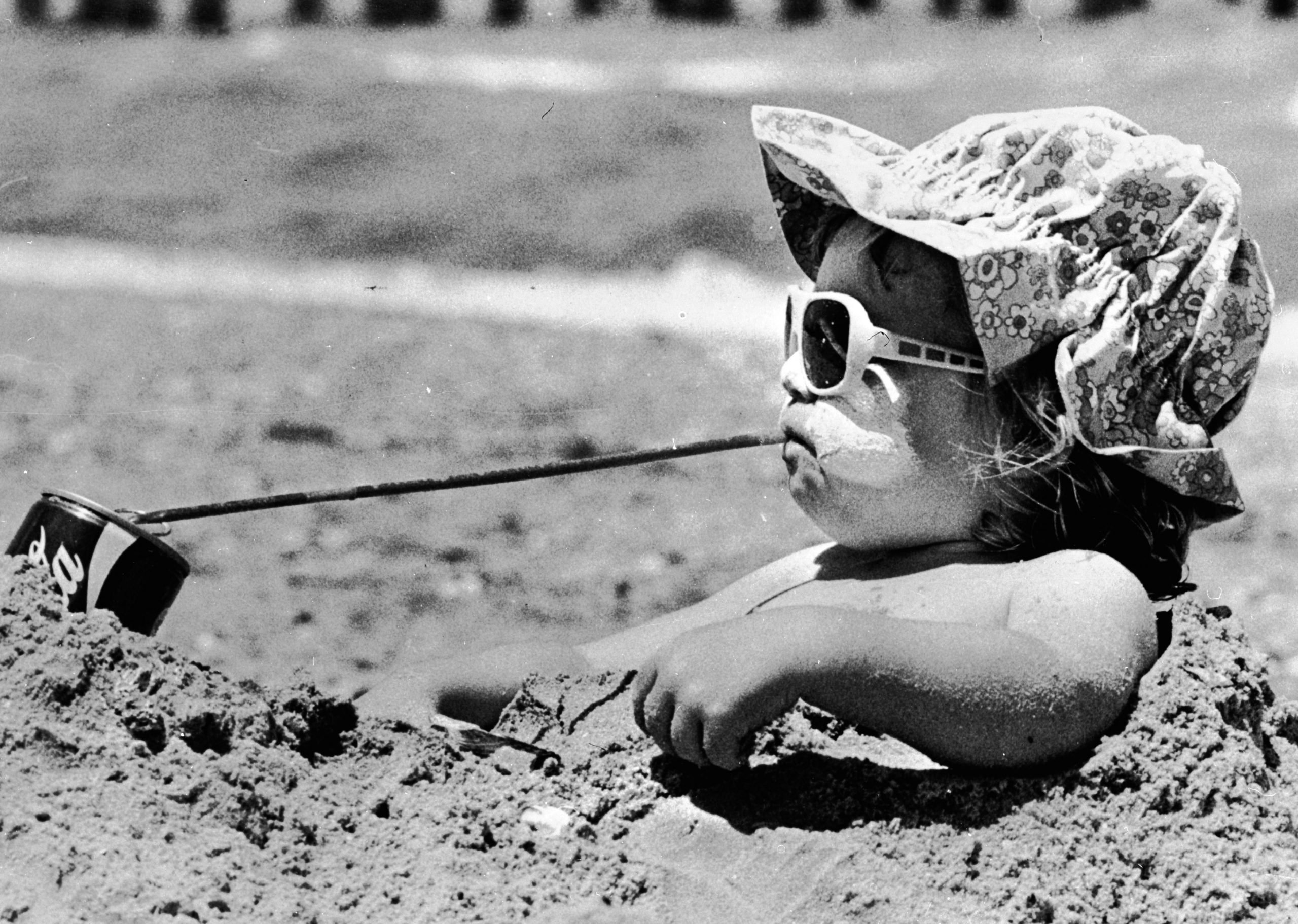 Niña bebiendo Coca-Cola en la playa