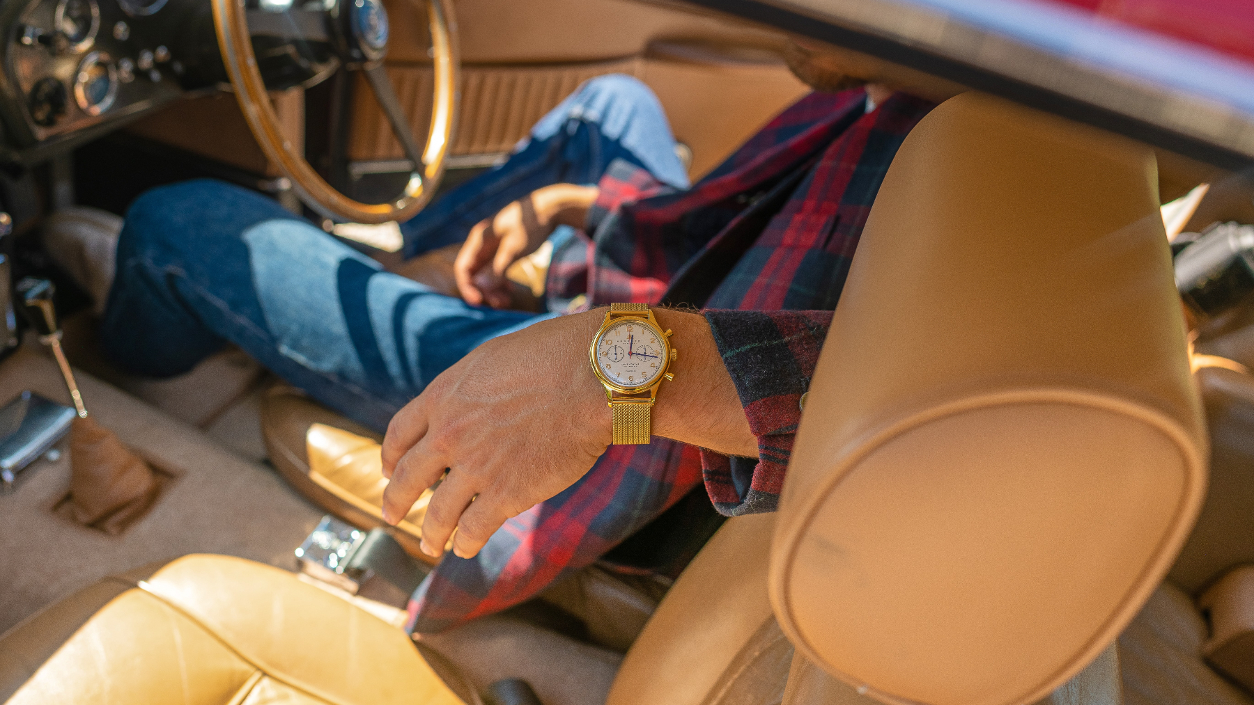 Hombre con reloj en coche con piel de cuero / Foto: Unplash