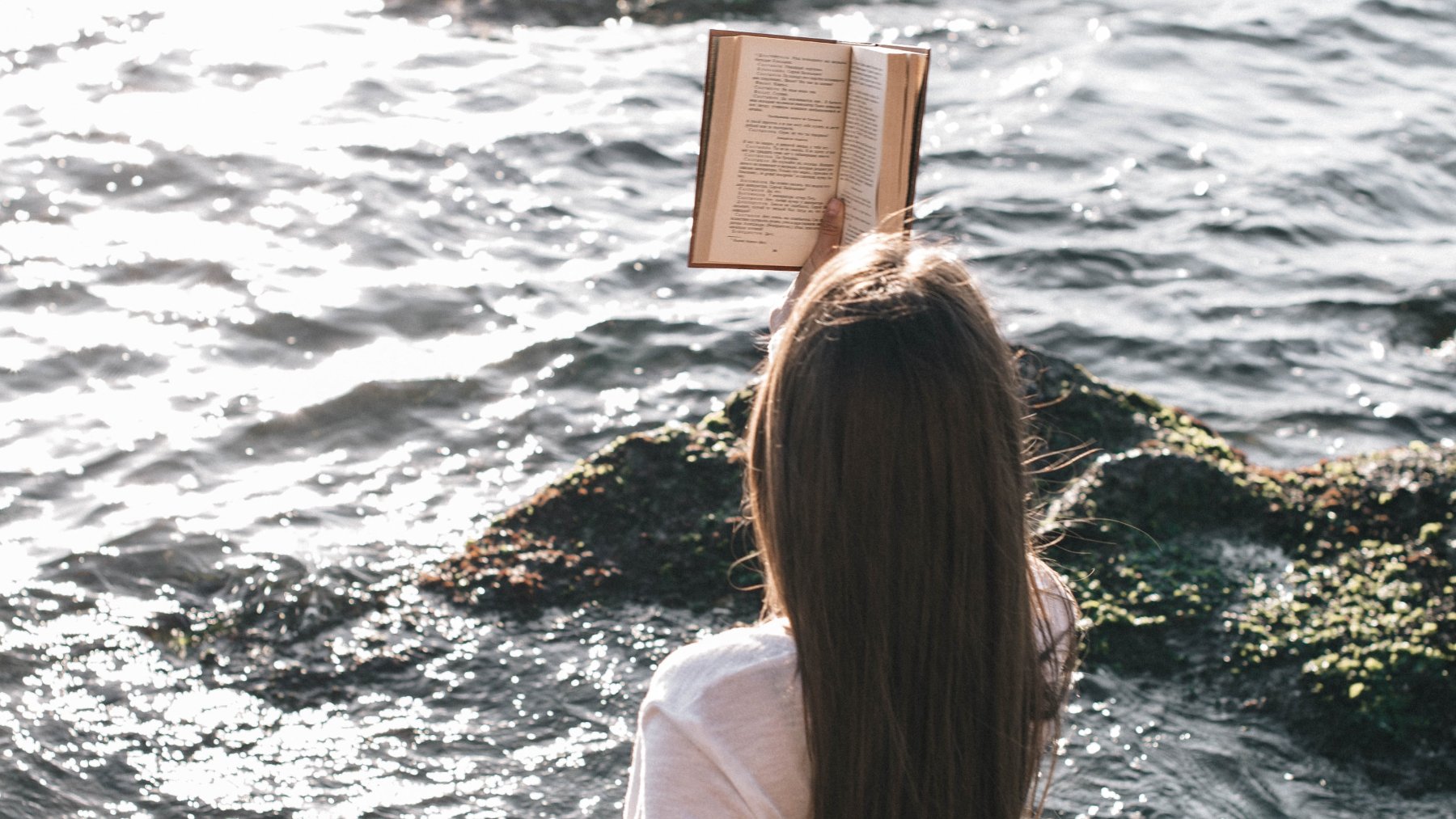 Mujer leyendo junto al mar