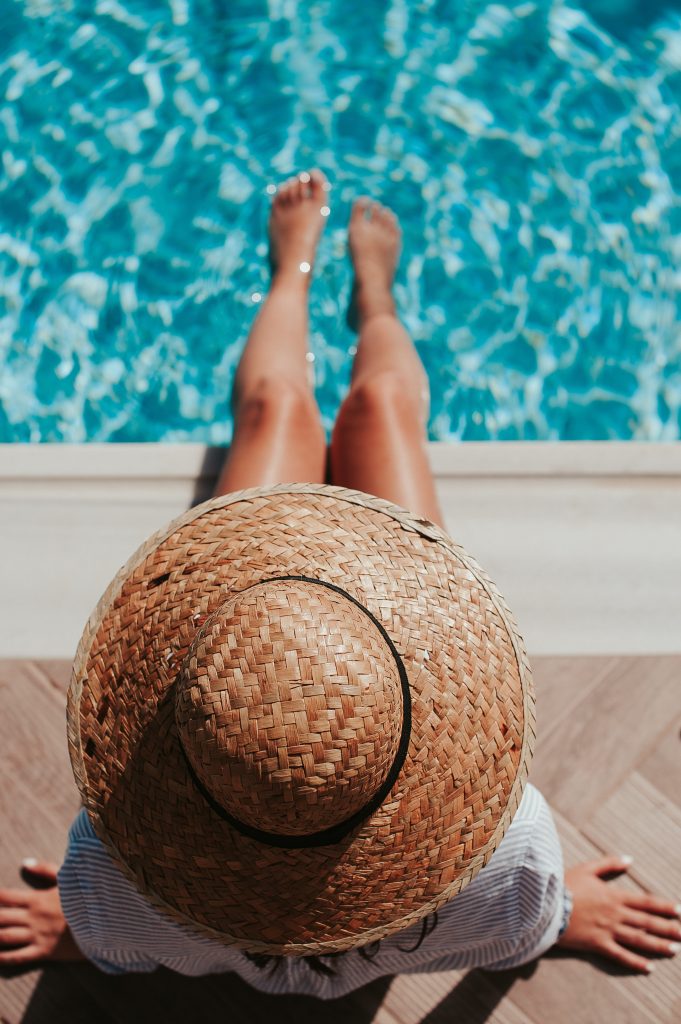 Chica con sombrero al sol en una piscina