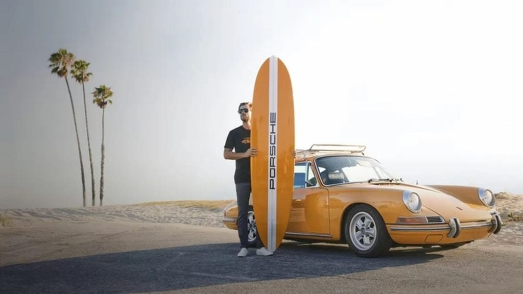 Hombre con Porsche 911 amarillo y tabla de surf