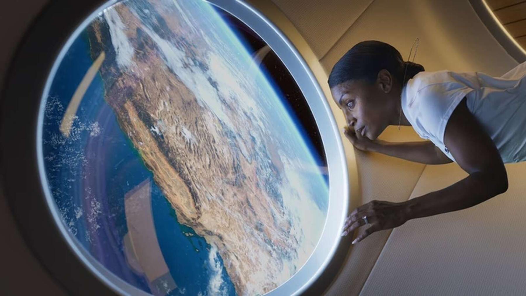 Mujer mirando por la ventana en la estación espacial Haven-1