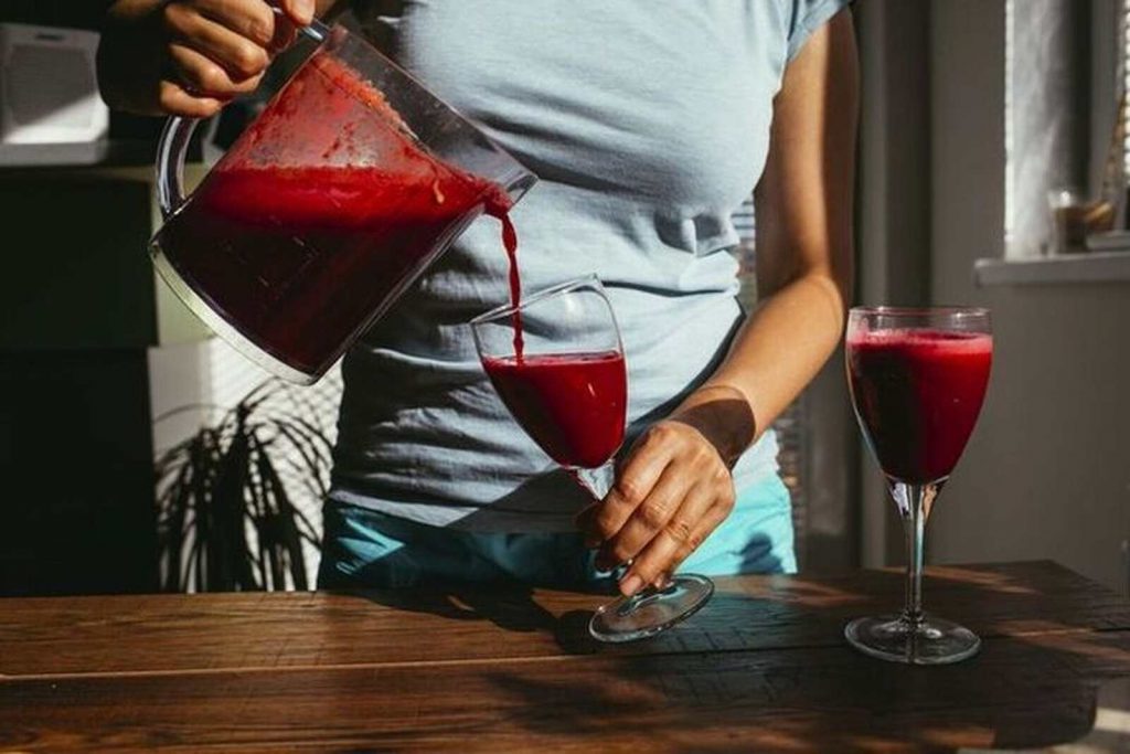 Mujer sirviendo zumo rojo para adelgazar