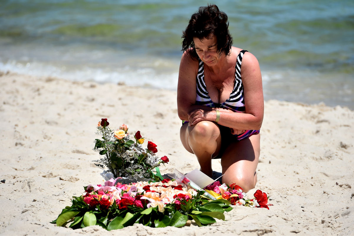 Una turista deja un ramo de flores sobre la arena de la playa donde fueron asesinados 37 turistas (Foto: Getty)
