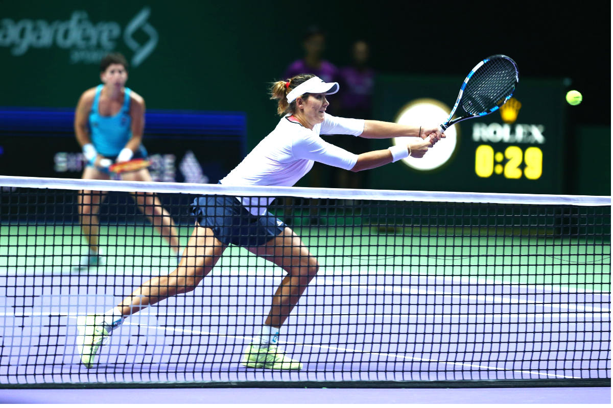 Garbiñe Muguruza, con Carla Suárez al fondo, volea en las semifinales del Masters. (Getty)