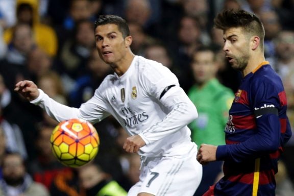 El delantero portugués del Real Madrid, Cristiano Ronaldo, disputa el balón con el defensa del FC Barcelona Gerard Piqué, en el partido de la jornada 12º de liga de Primera División que les enfrenta en el Estadio Santiago Bernabéu. EFE