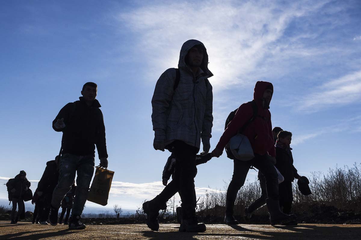 Imagen de unos refugiados caminando por medio de un campo. (Foto: AFP)