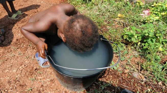 Un niño trata de beber agua en un cubo en el centro católico Don Bosco, de Bangui, Centroáfrica. (Foto: AFP)