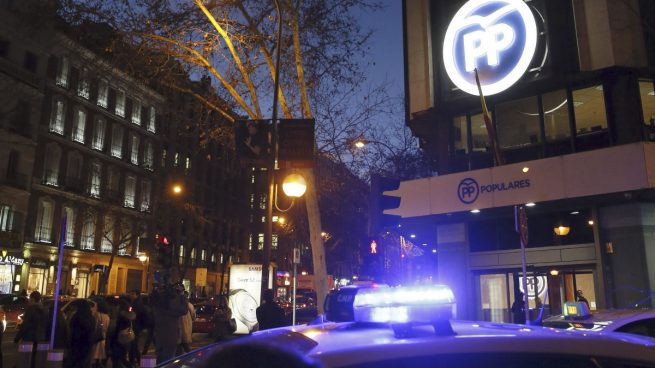 Un coche de la Policía, aparcado ante la sede del PP en Madrid, este jueves. (Foto: EFE)
