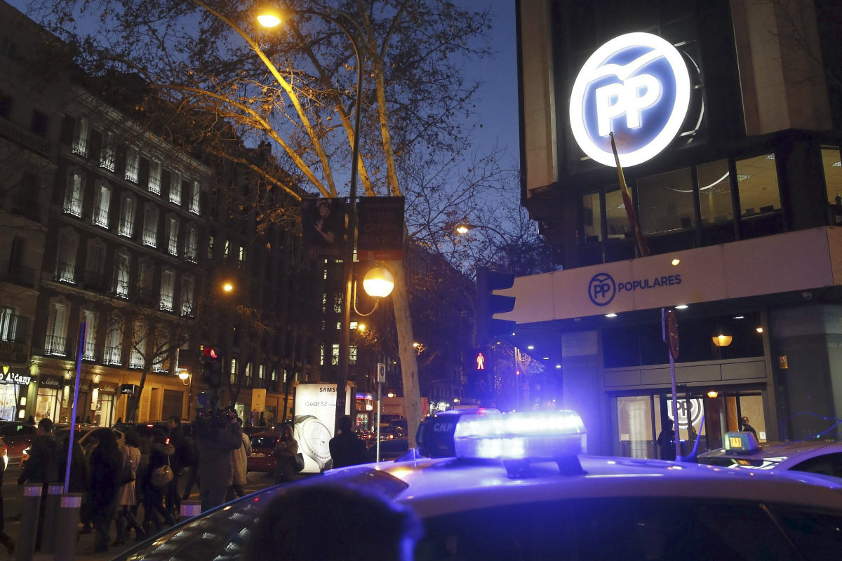 Un coche de la Policía, aparcado ante la sede del PP en Madrid, este jueves. (Foto: EFE)