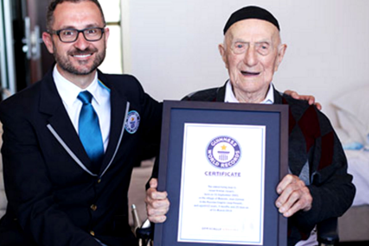 Israel Kristal sosteniendo su título de hombre más viejo del mundo otorgado por Marco Frigatti, director de los Records Guinness.