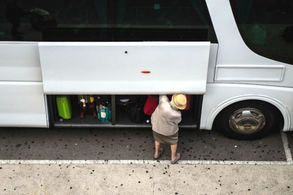 Una pasajera guarda su equipaje en un autobús.