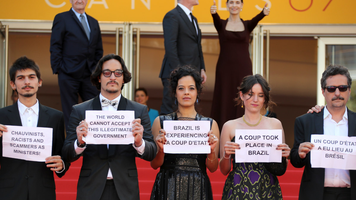 El equipo de Aquarius aprovecharon la atención mediática de la alfombra roja de Cannes para mostrar pancartas contrarias a la destitución de Dilma Roussef. Detrás, la actriz Sonia Braga apoya a sus compatriotas. (Foto: AFP)