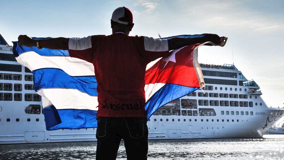 Un cubano muestra la bandera de Cuba desde el malecón para recibir al Adonia Phatom. (Foto: AFP)