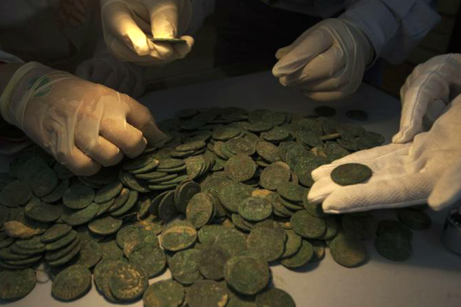 Técnicos del Museo Arqueológico de Sevilla analizan las monedas descubiertas en este magnífico hallazgo. (Foto: AFP)