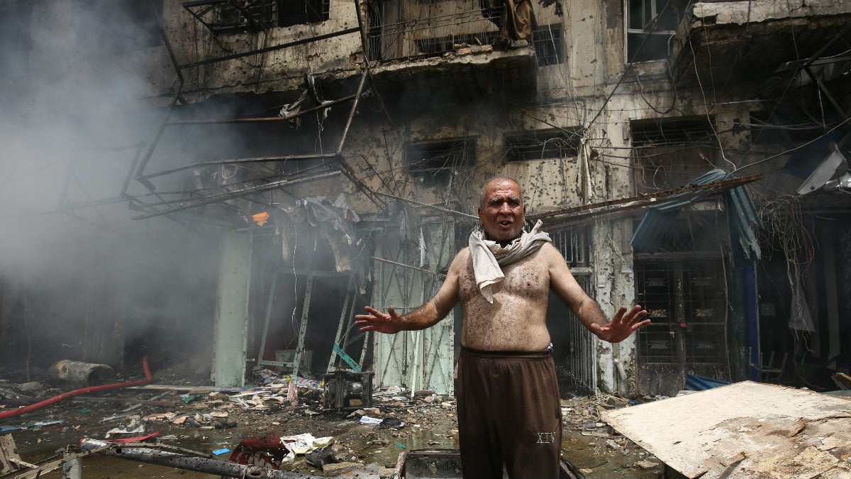 Un irakí delante de uno de los edificios totalmente calcinados por uno de los coches bombas que este jueves han explotado en Bagdad. (Foto: AFP)