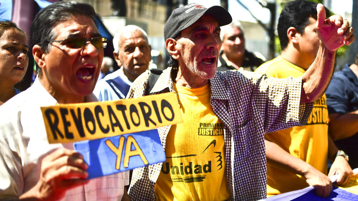 Un hombre exhibe una pancarta exigiendo el revocatorio contra Maduro (Foto: AFP).