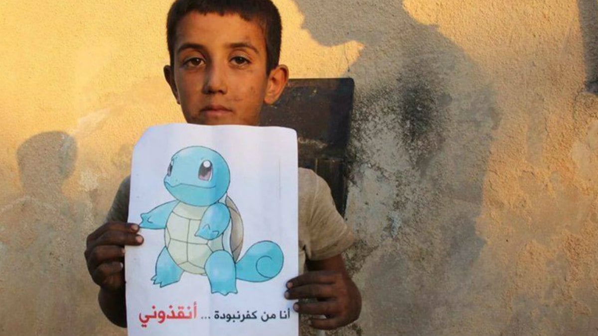 Un niño sirio sostiene un cartel con Squirtle, un ejemplar más de las criaturas que poblan el mundo de Pokémon Go, en el que se lee, en sirio, el mensaje Estoy en Siria, ven a salvarme.