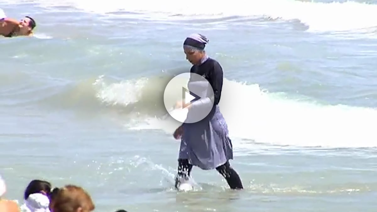 Una joven se baña con un burkini en una playa de Alicante.