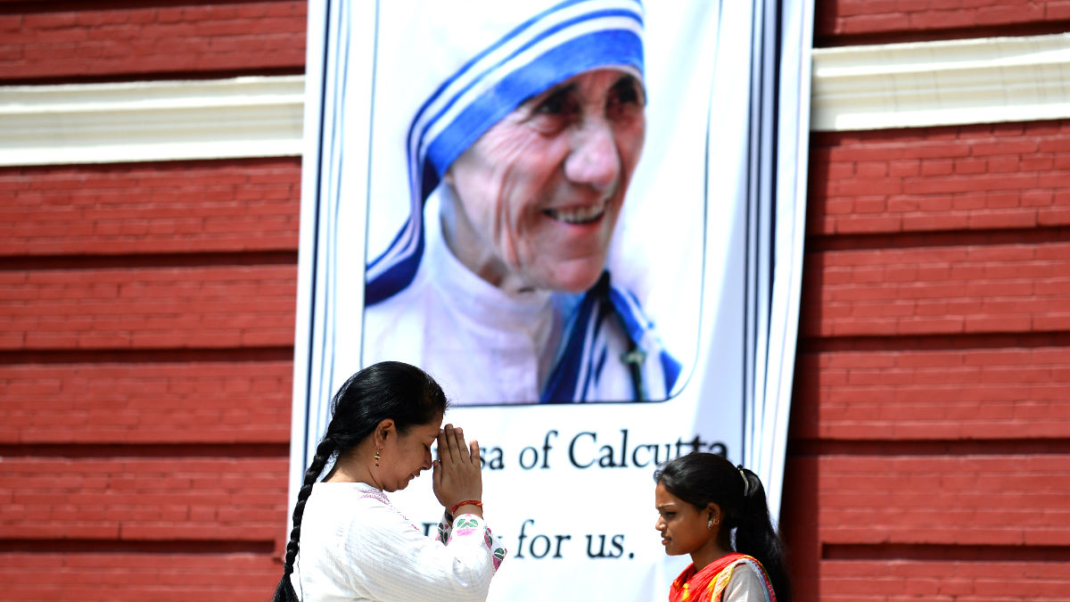 Dos mujeres rezan ante un cartel con la imagen de la Madre Teresa de Calcuta (Foto: AFP).