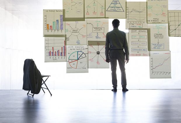 Businessman looking at graphs and charts on glass wall in office