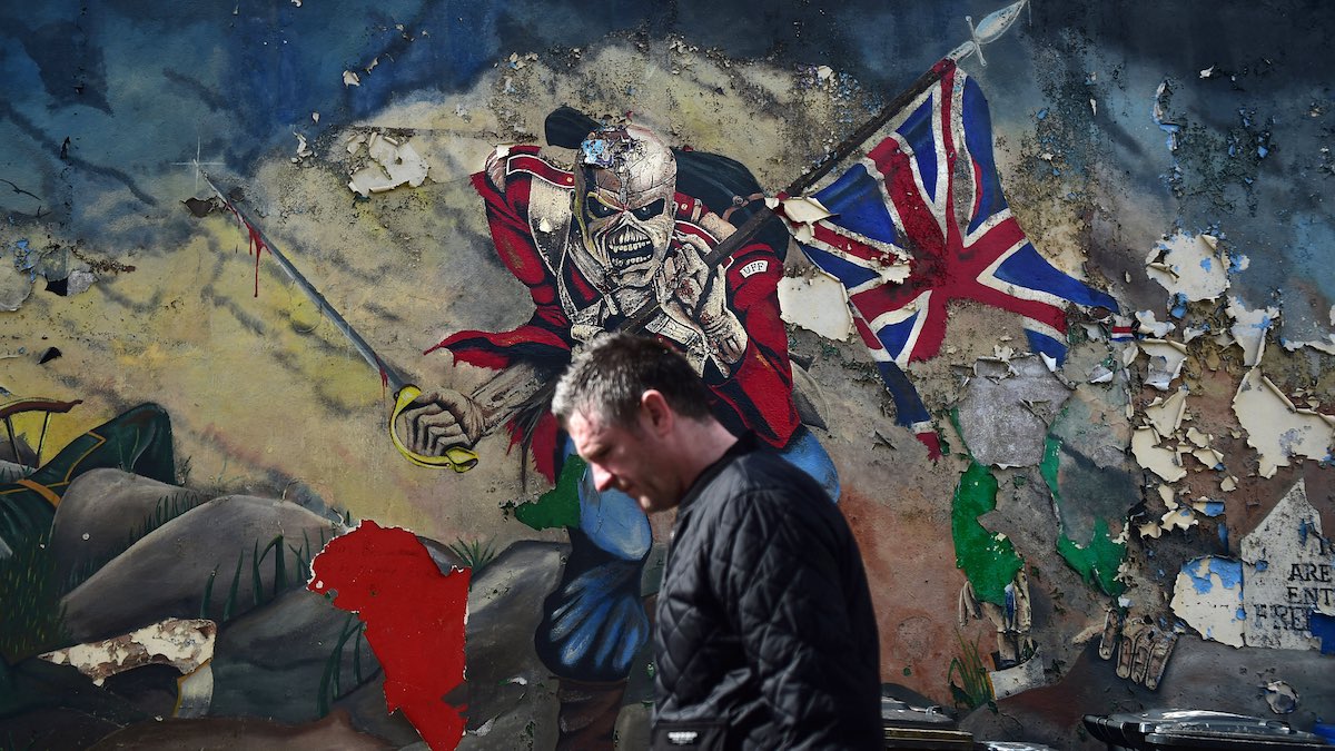 Un hombre camina delante de un grafitti que ilustra una portada de un disco del grupo británico Iron Maiden. (Foto: Getty)