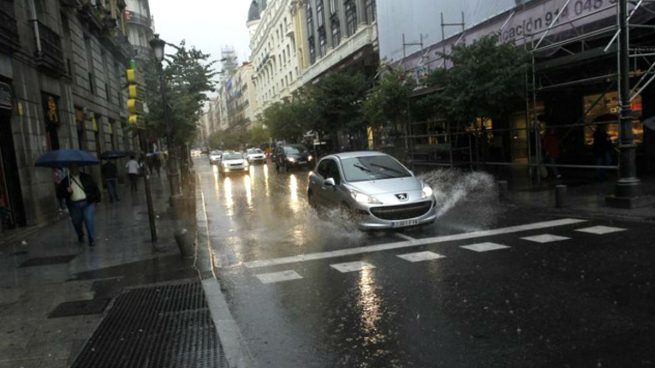 Coches circulando por una calle un día de lluvia.