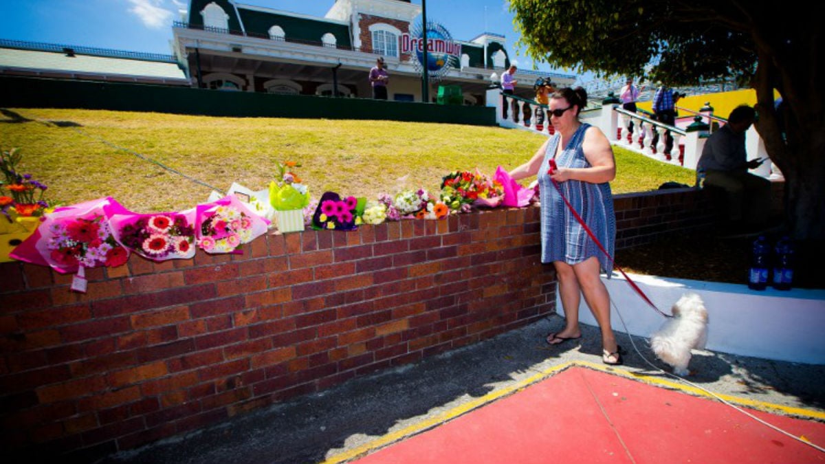 Familiares de las víctimas y afectados por el terrible accidente depositan flores en un muro del parque de atracciones Dreamworld, el más grande de Australia. AFP