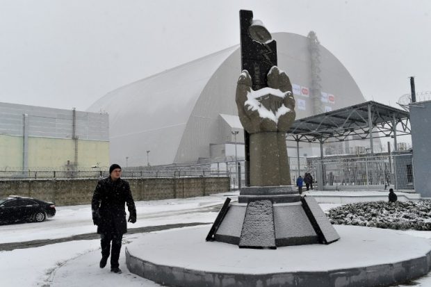 Un hombre pasea por el exterior de la cúpula instalada sobre el reactor nuclear accidentado de Chernóbil en Ucrania. Foto: AFP