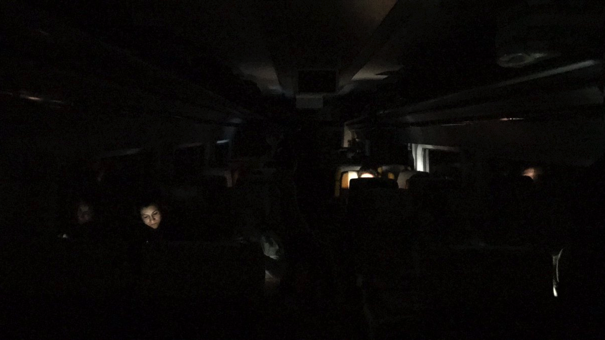 Pasajeros en un vagón de tren atrapado alumbrados por sus móviles y ordenadores. (Foto: TW)