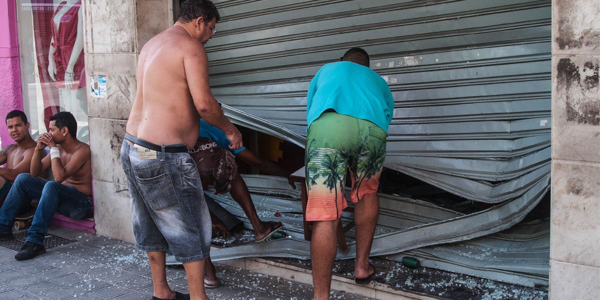 Unos hombres arreglan el cierre de una tienda saqueada cerca de Vitoria, capital del estado de Espírito Santo. (Foto: AFC)