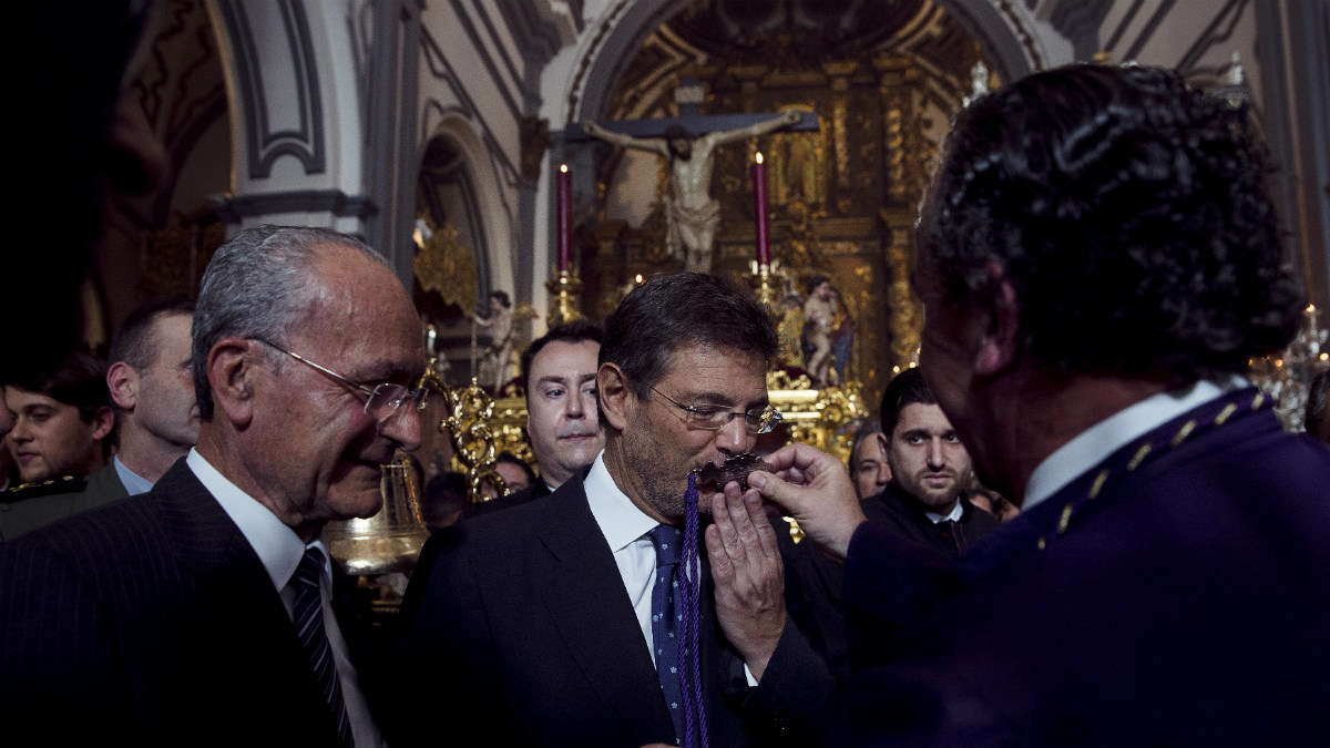 El ministro de Justicia, Rafael Catalá, besa la medalla de la Hermandad Sacramental y Reales Cofradías Fusionadas junto al alcalde de Málaga, Francisco de la Torre (d), en la salida del Santísimo Cristo de Ánimas de Ciegos en la Iglesia de San Juan de Málaga (Foto:EFE)