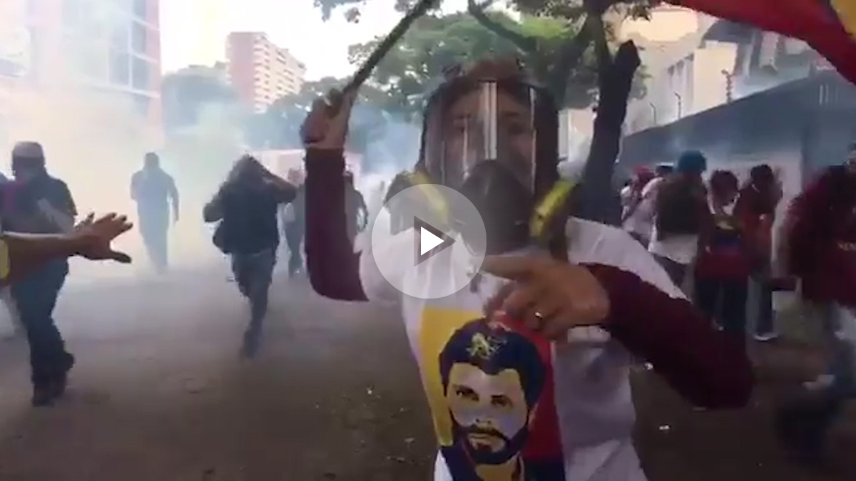Lilian Tintori, con máscara antigás, enarbola una bandera venezolana ante la represión de las fuerzas de Maduro.