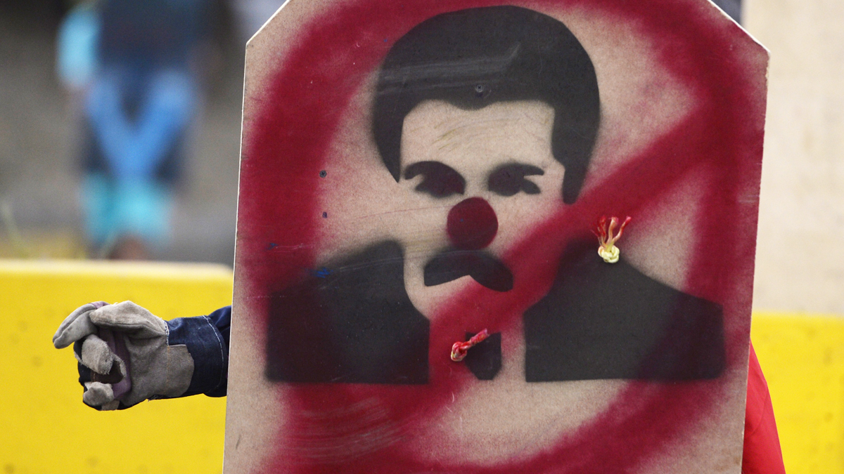 Un manifestante con un ‘escudo’ con una pintada que ridiculiza a Nicolás Maduro. (Foto: AFP)