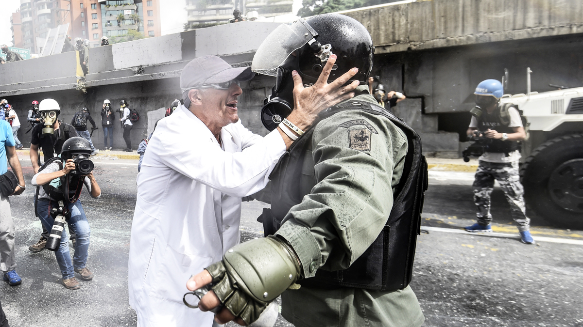 Un médico trata de hablar con un agente en una de las protestas en Caracas. (Foto: AFP)