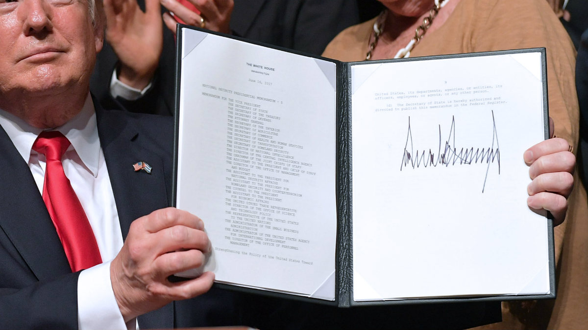 Trump muestra orgulloso su enorme firma en el decreto para frenar el deshielo con Cuba, en el teatro Manuel Artime de Miami. (AFP)