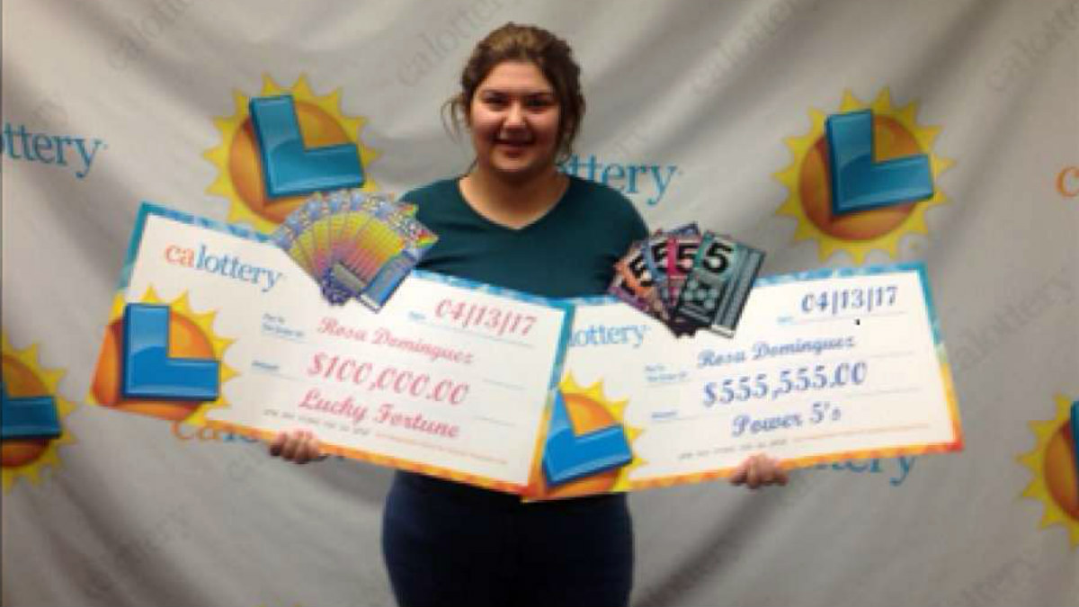 Rosa Domínguez posando con sus dos cheques de sus sendos premios en las Loterías de California.