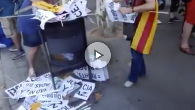 Dos mujeres rompen pancartas en español que están en la basura tras la manifestación del sábado contra el terrorismo.