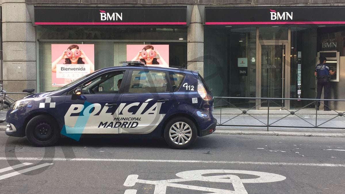 Un agente de la Policía Municipal para en un carril bus para sacar dinero de un cajero.