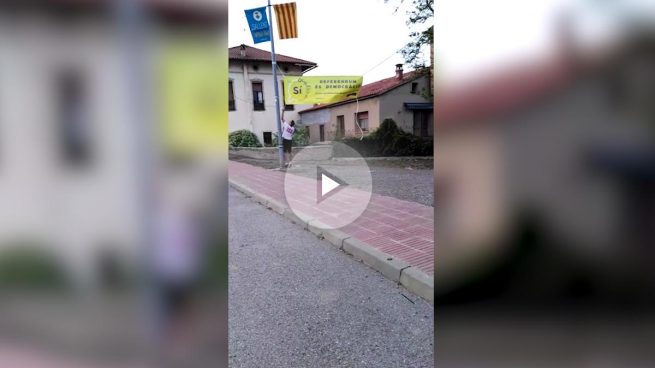 Un joven constitucionalista arranca una pancarta a favor del referéndum en un pueblo catalán