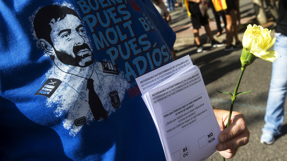 Una independentista con una camiseta de apoyo los Mossos d’Esquadra y una papeleta del referéndum en la mano. (Foto: EFE)