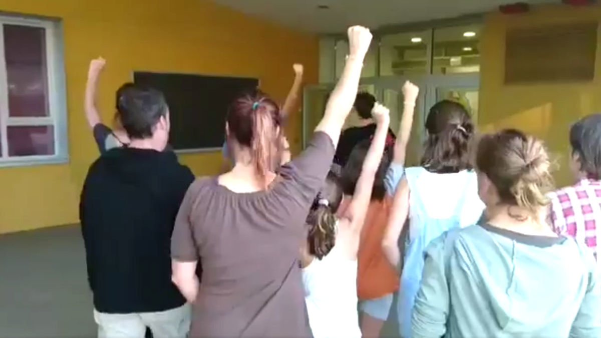 Un grupo de padres mete a sus hijos en la escuela El Morrot de Olot alzando el puño.