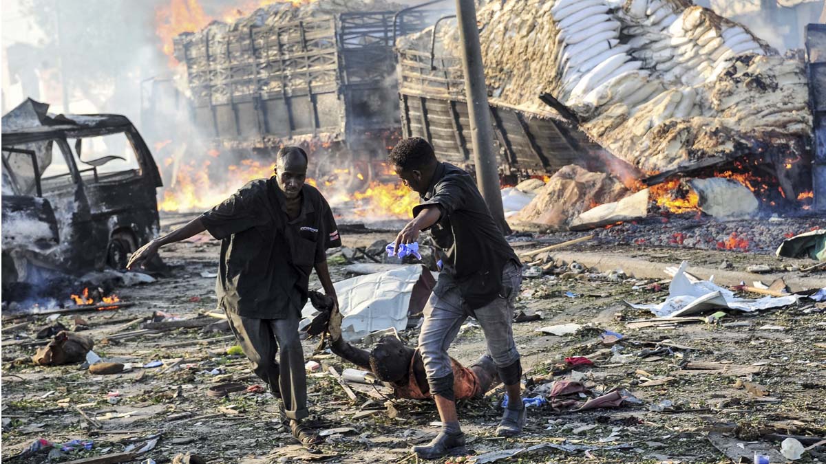 Dos hombres arrastran a una de las víctimas del atentado en Mogadiscio. (Foto: AFP)