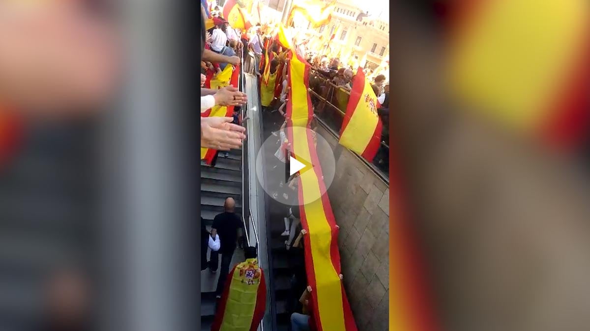 Un grupo de jóvenes llega a la manifestación de Barcelona portando una gran bandera de España.