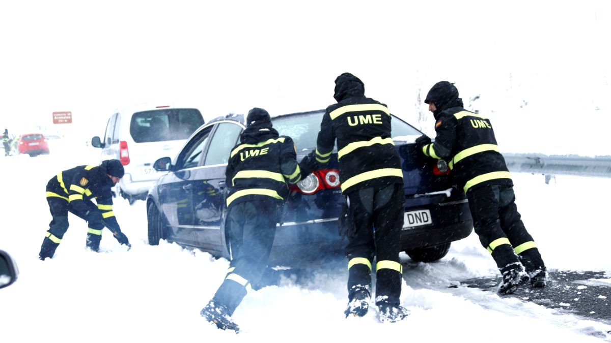 Efectivos de la UME empujan un coche atrapado por la nive en la AP6 (Foto: Efe).