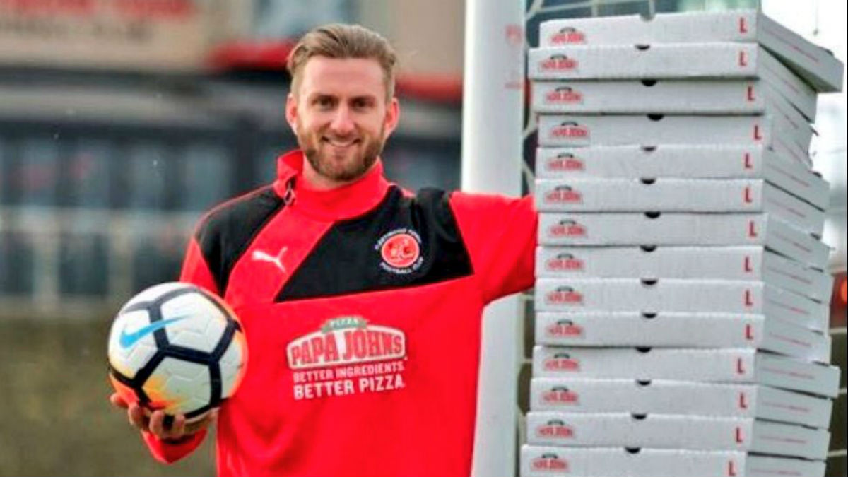 El portero del Fleetwood Town posa junto a una torre de cajas de pizza. (Foto: Fleetwood Town)