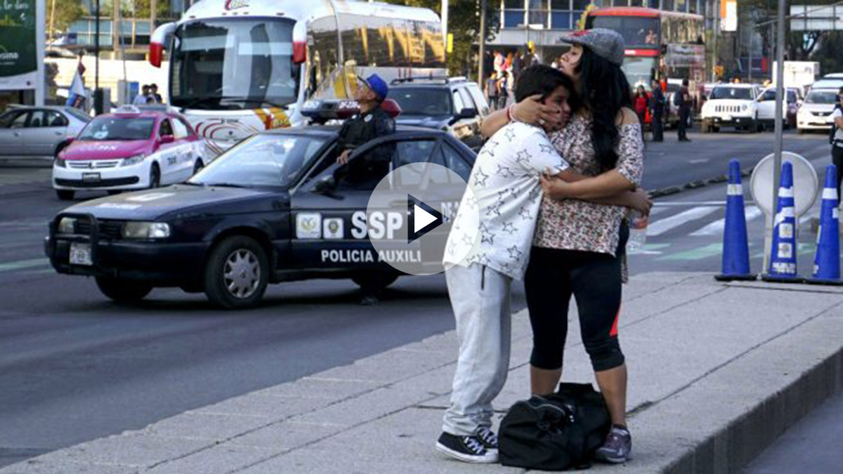 Una mujer y un niño se abrazan ante un coche de policía (Foto: AFP).