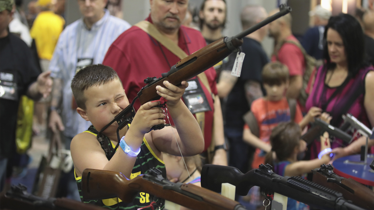 Un niño sostiene un arma en una feria de la Asociación Nacional del Rifle. (Foto: AFP)