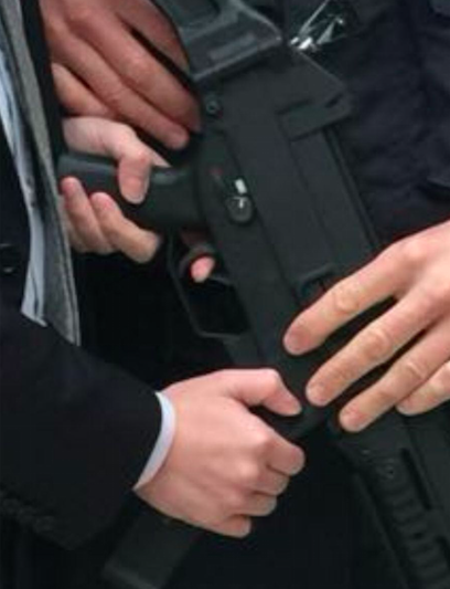 Detalle del congresista empuñando el subfusil y con los dedos en el gatillo