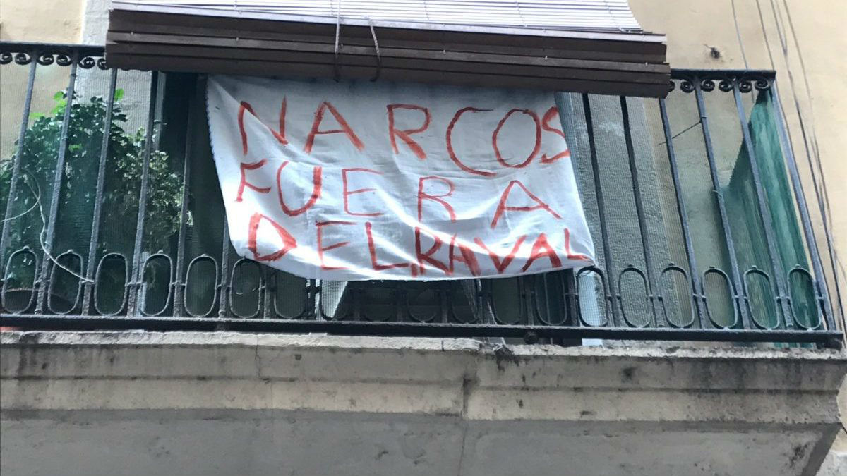 Una pancarta colgando de un balcon del Raval de Barcelona protestando por los narcopisos